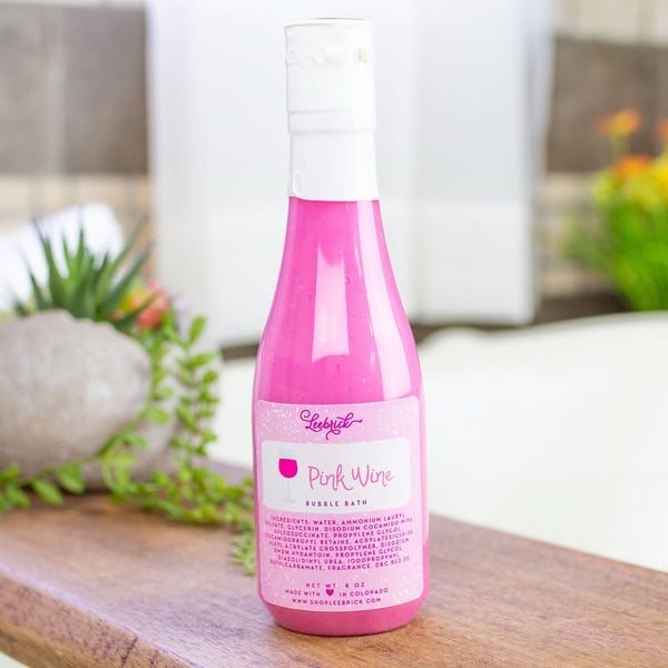 Bottle of Pink Wine Bubble Bath displayed by bathtub
